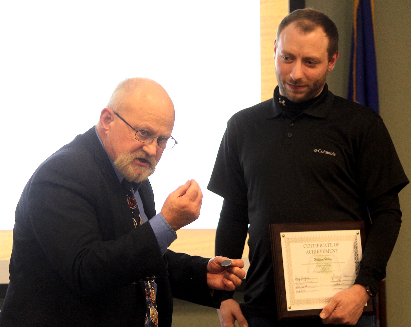 Shawano-Menominee Circuit Court Judge William Kussel Jr., left, presents William Hilley with a medallion, shown in Kussel’s left hand, recognizing that Hilley has completed all the requirements for the Shawano County Drug Treatment Court program during a graduation ceremony Nov. 19 at the Shawano County Human Services Complex.  (Lee Pulaski | NEW Media)